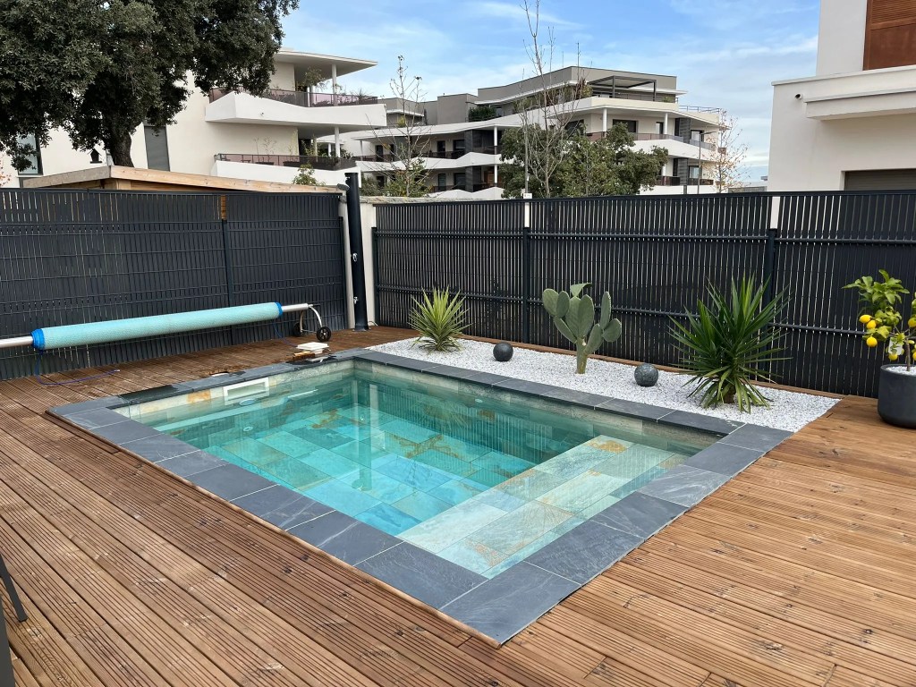 Piscine moins de 10m² avec banquette et carrelage Bali entouré d'une terrasse en bois